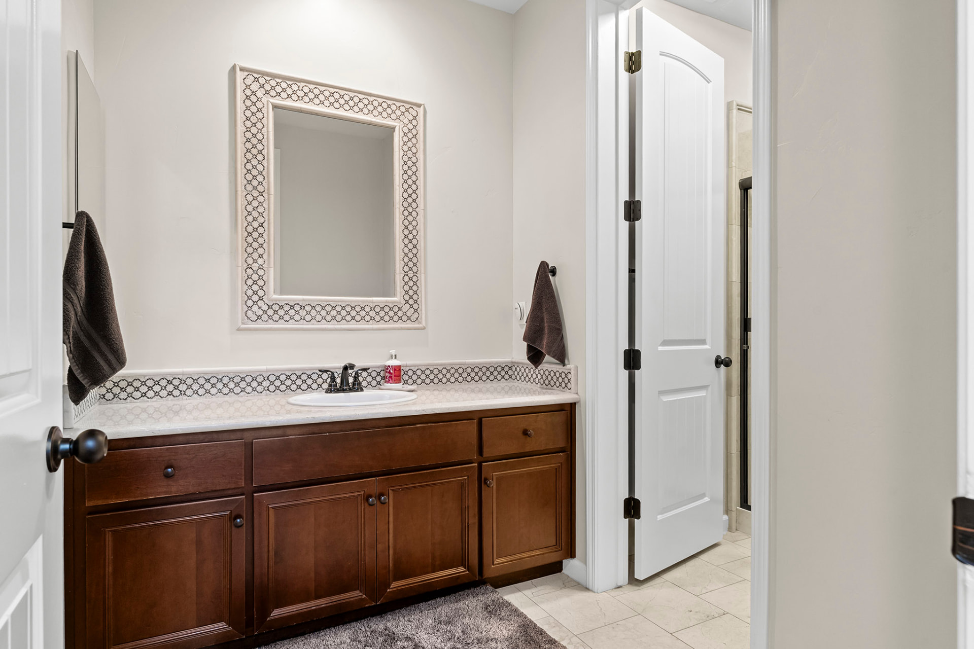Guest bath vanity with a stone mosaic backsplash and framed mirror