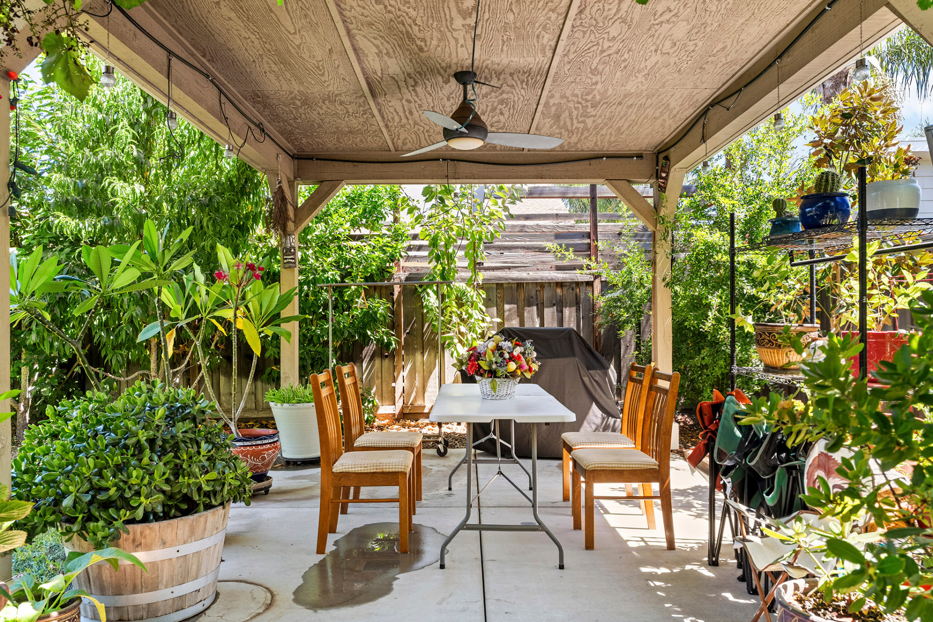 Covered backyard patio with an outdoor dining table and ceiling fan