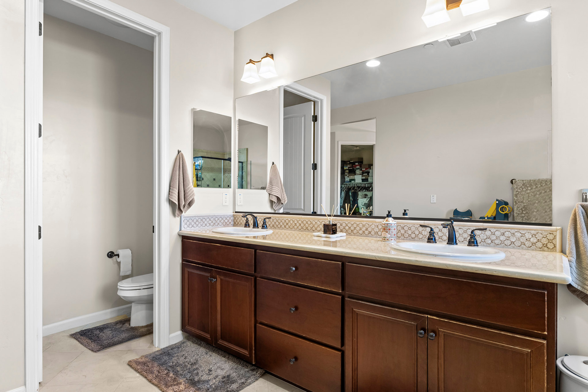 Primary bath dual vanity with a private water closet and walk-in closet beyond