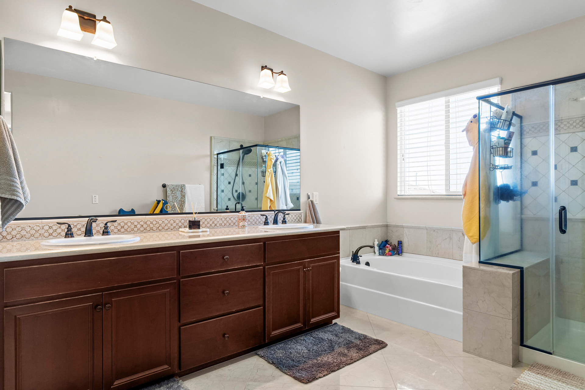 Primary bath with dual vanities, a soaking tub, and a glass shower