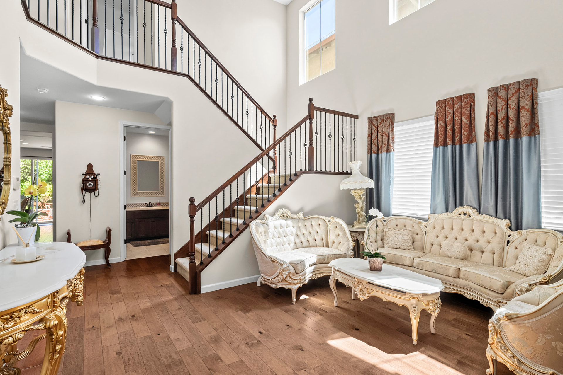 Entry and living room with a curved staircase and wrought-iron railing