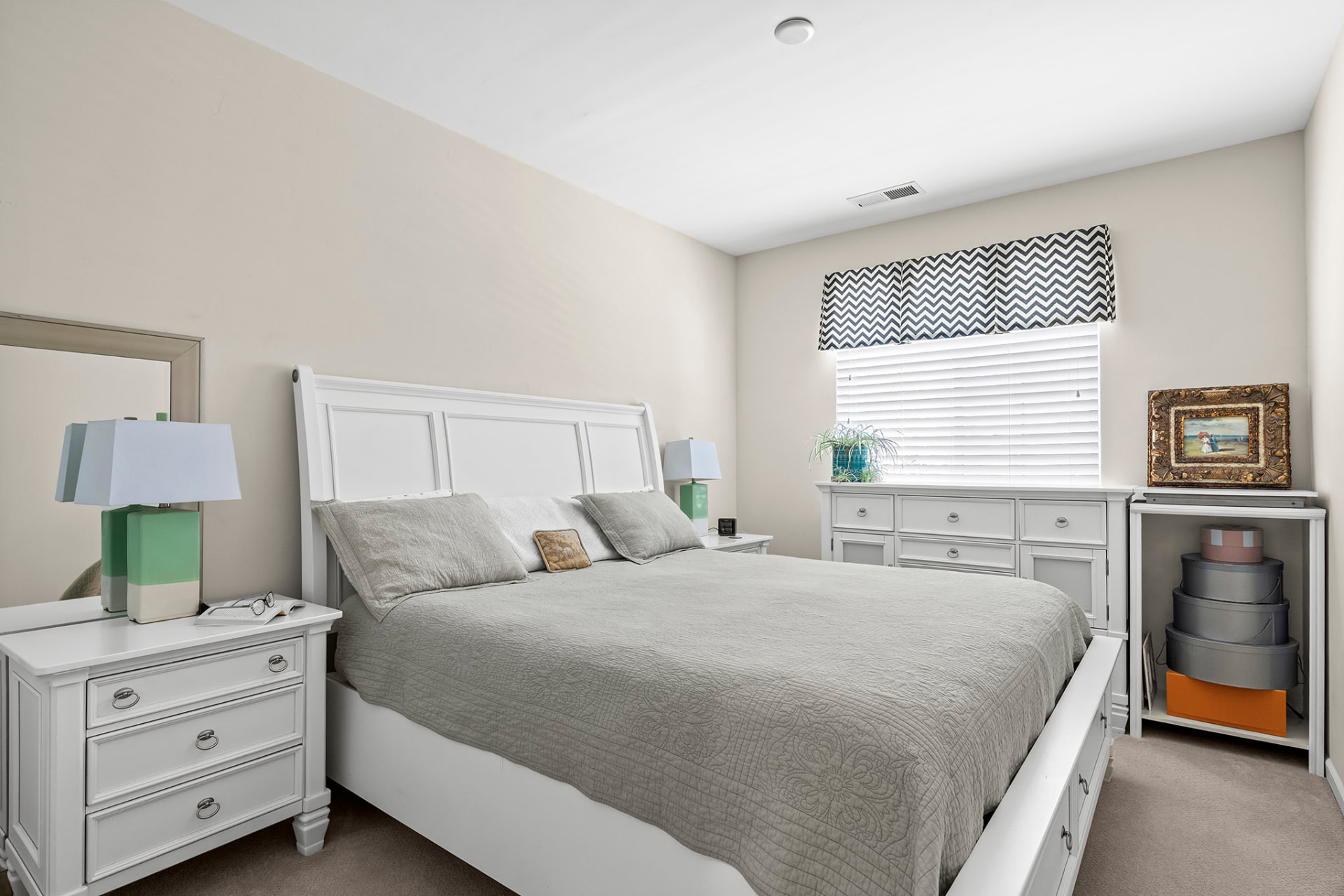 Bedroom with a king bed, white furniture, and a bright window