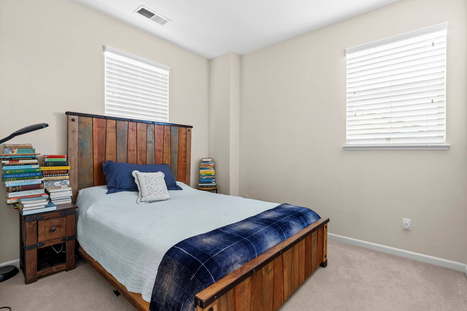 Guest bedroom with a reclaimed wood bed frame and two windows