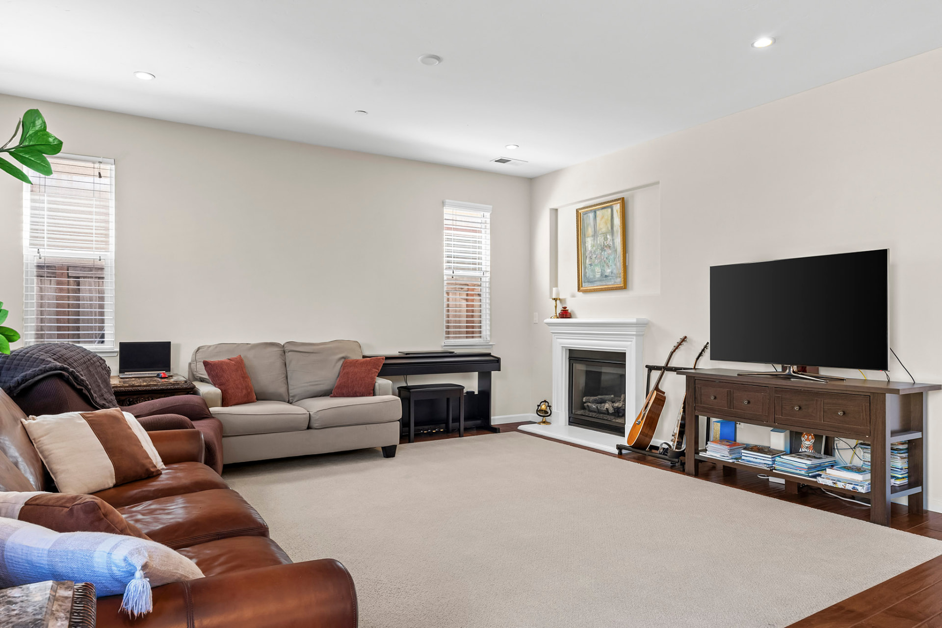 Open family room with a fireplace, carpet, and large windows