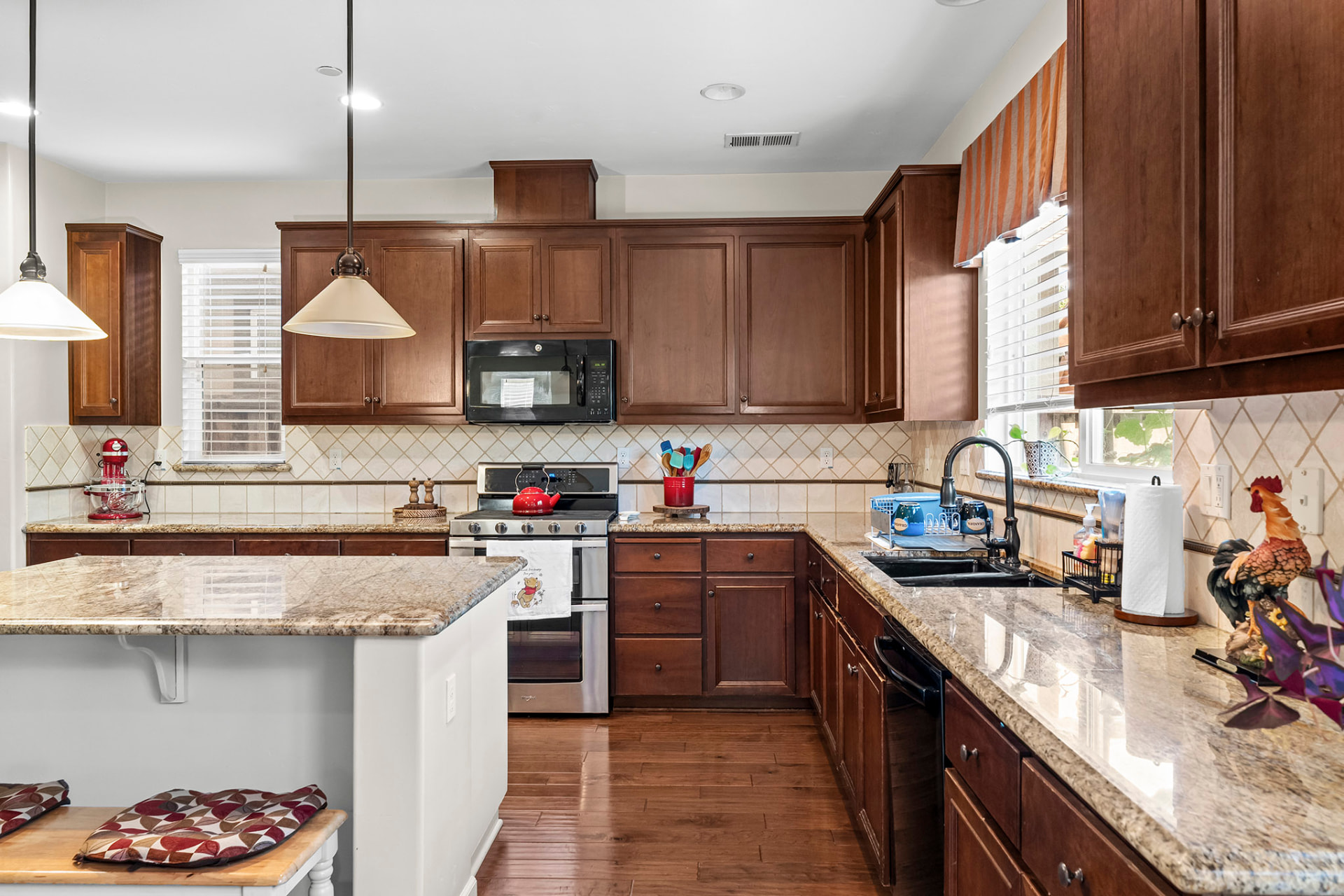 Wide view of the kitchen with breakfast bar, double ovens, and cherry cabinets