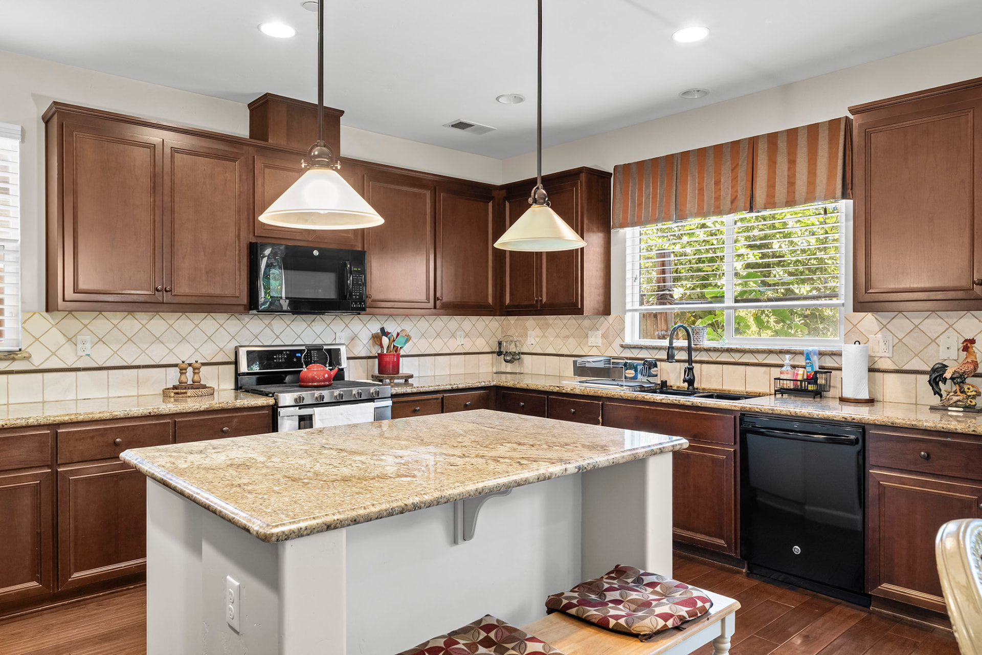 Kitchen with a large granite island, pendant lighting, and cherry cabinetry