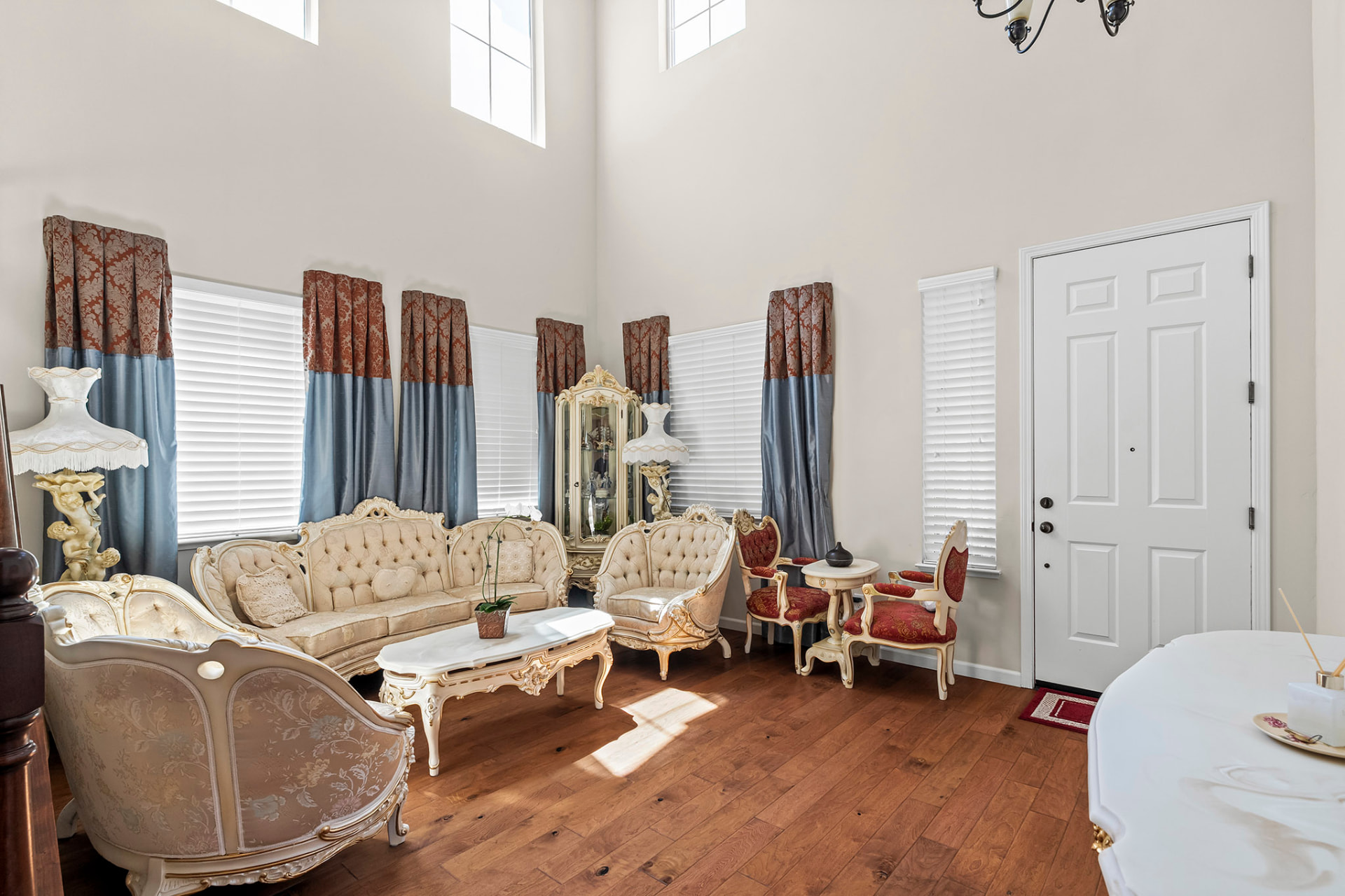 Formal living room with soaring two-story windows and hardwood floors